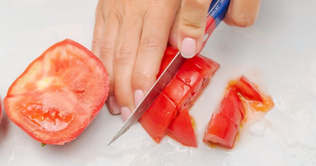 dicing fresh tomato on cutting board