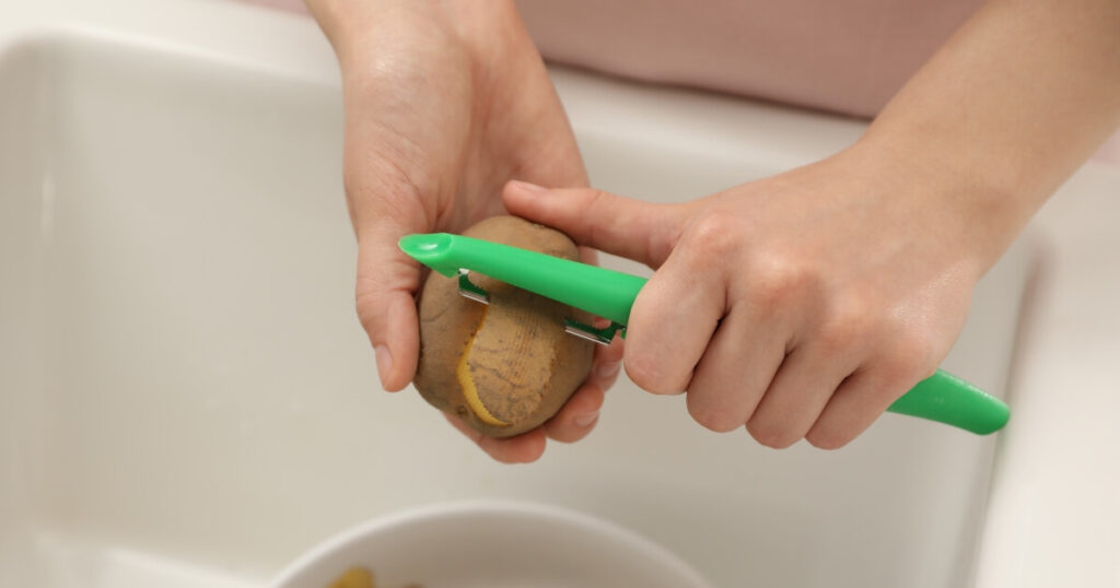 peeling whole potatoes in sink