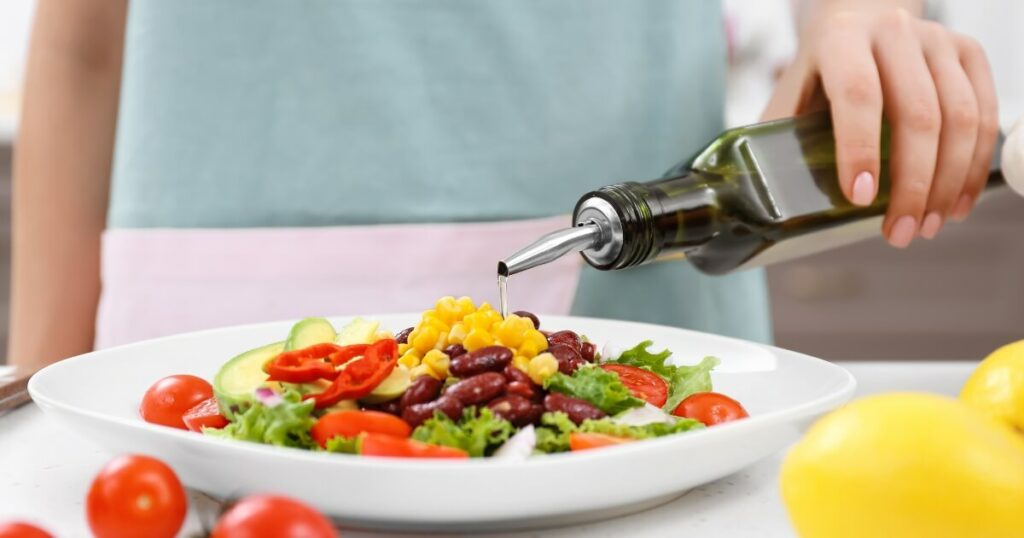 pouring oil over salad with oil bottle