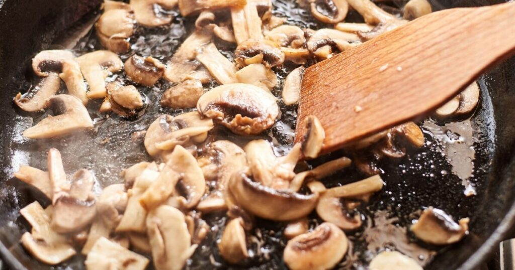 sauteing mushrooms with wooden spoon