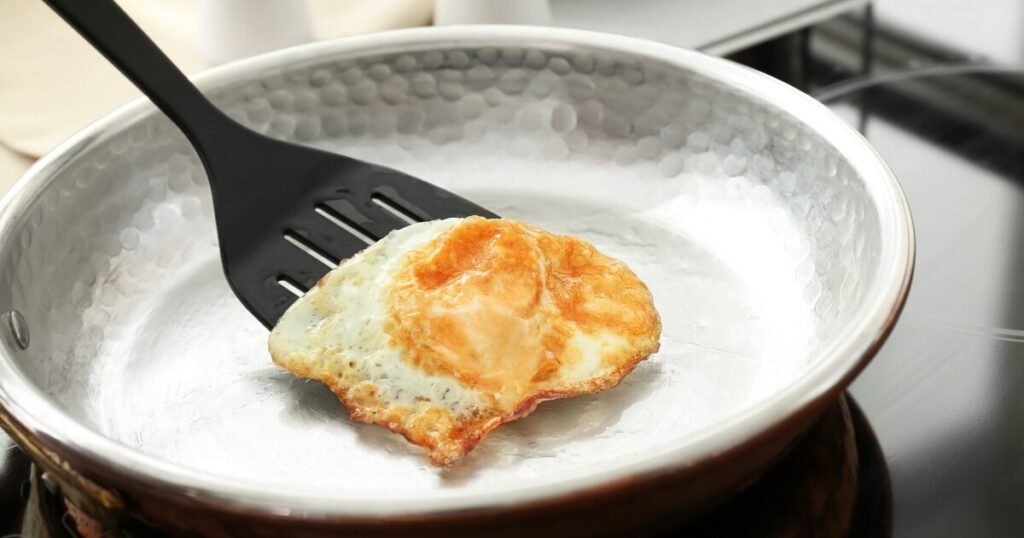 spatula flipping egg in pan