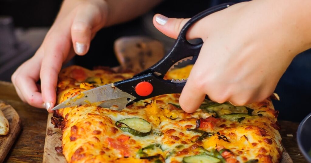 using kitchen scissors to cut pizza