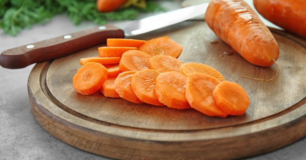 wooden cutting board with sliced carrots and knife